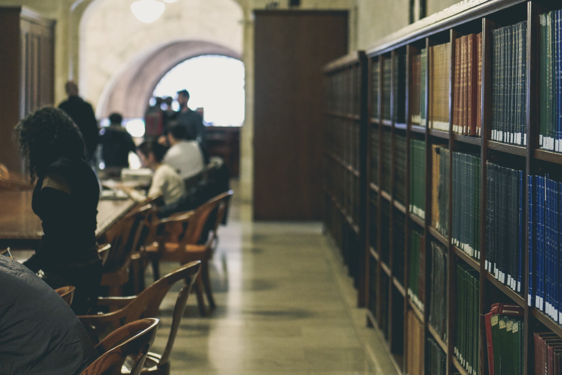 Readers seated beside bookshelves in the New York Public Library.