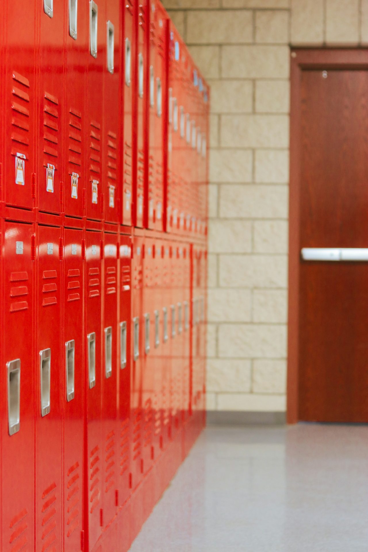 A long row of bright red lockers lining an empty school hallway