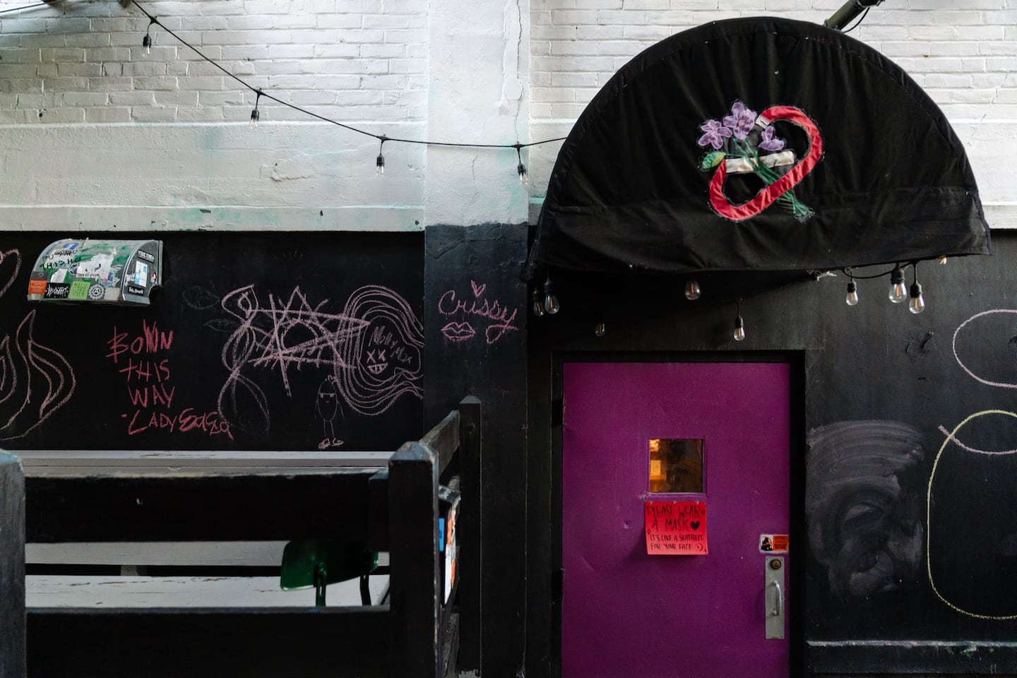 Exterior of Last Ditch Bar in Greenfield, Massachusetts, with a purple door and a sign asking patrons to wear a mask