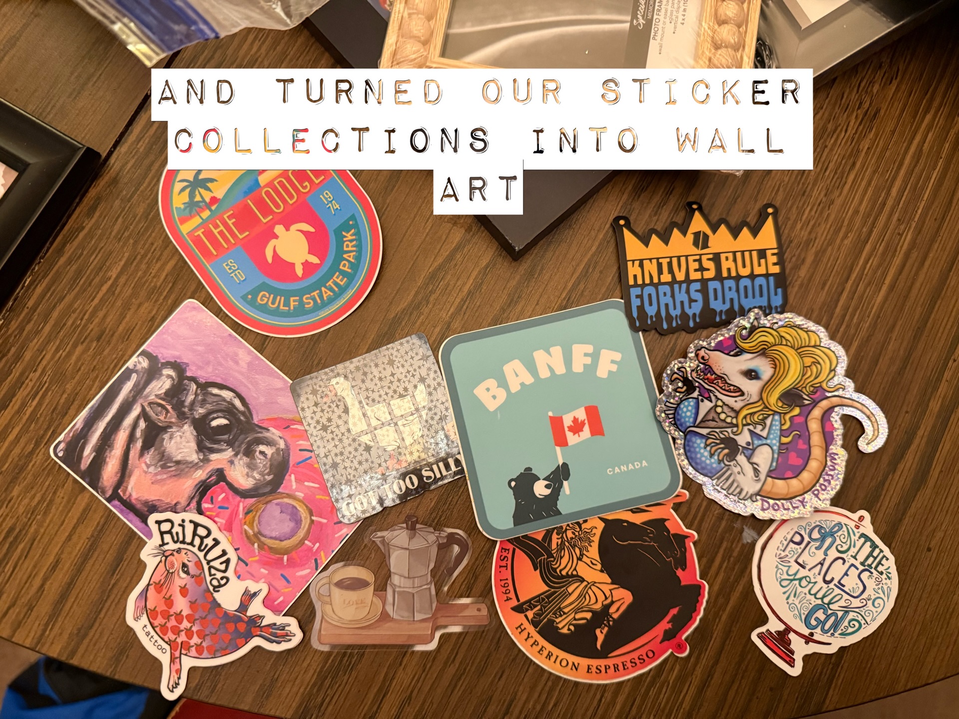 Stickers and small frames arranged on a wooden table for Silly Goose Girls Night's gallery-wall project.